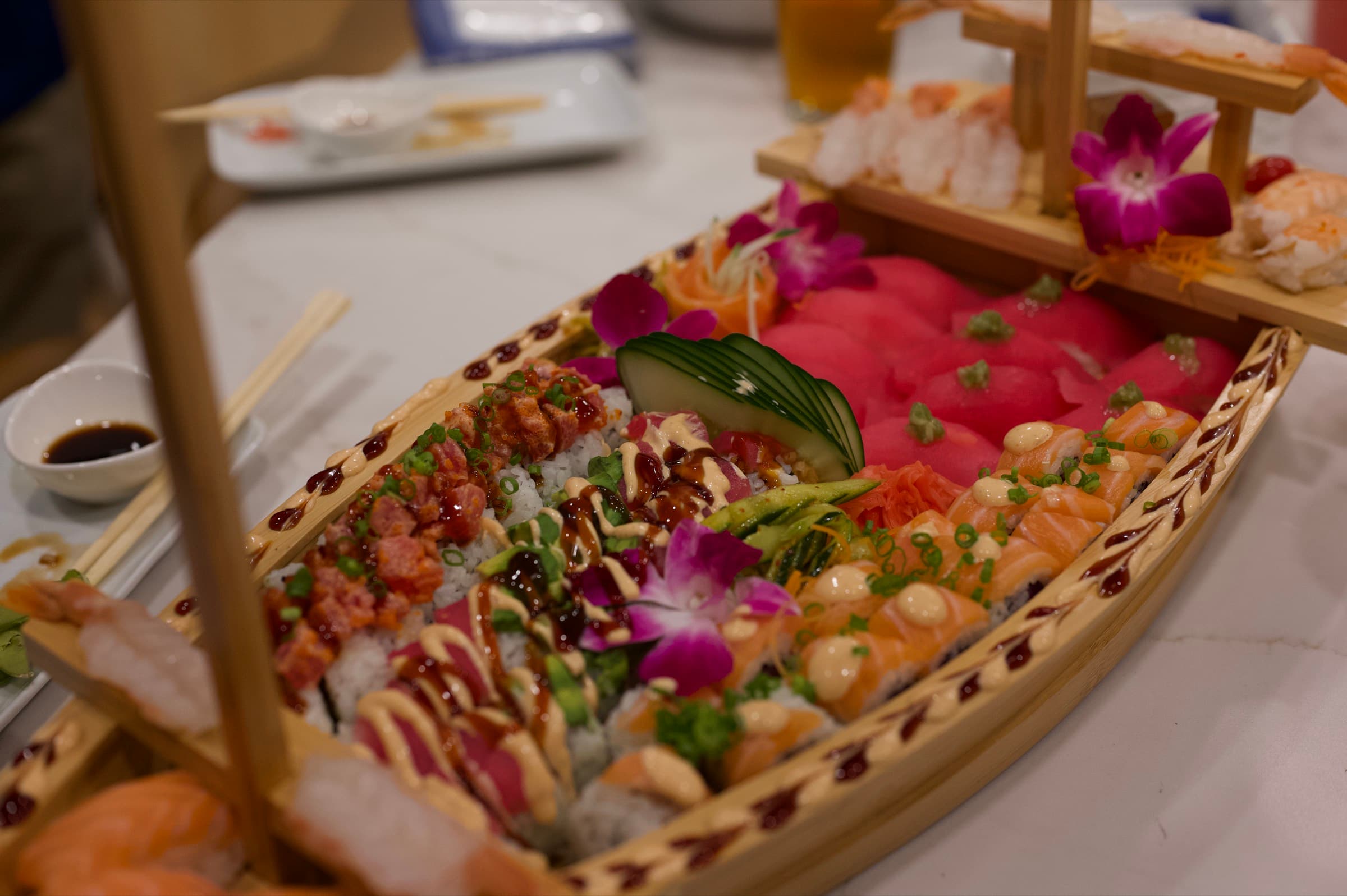 A sushi boat loaded with tuna, salmon and specialty rolls, finished with orchids.
