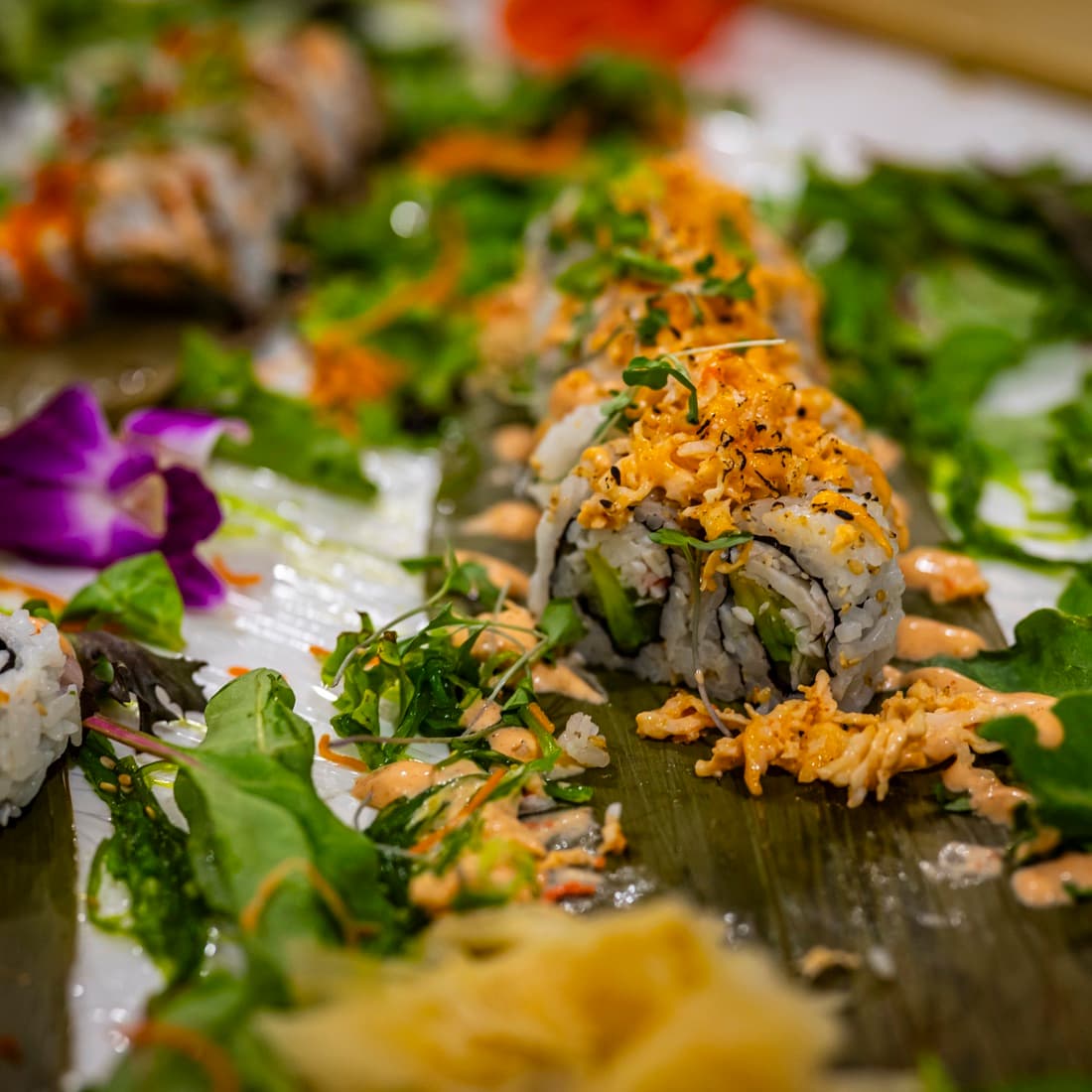 Hand-cutting fresh sushi rolls on the board during service.
